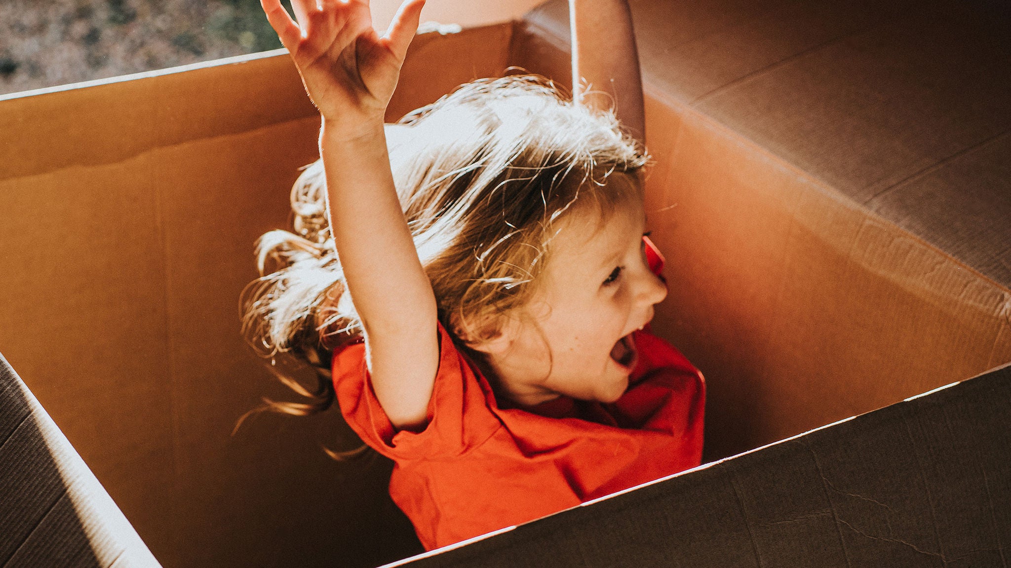 Photo of child playing in cardboard box