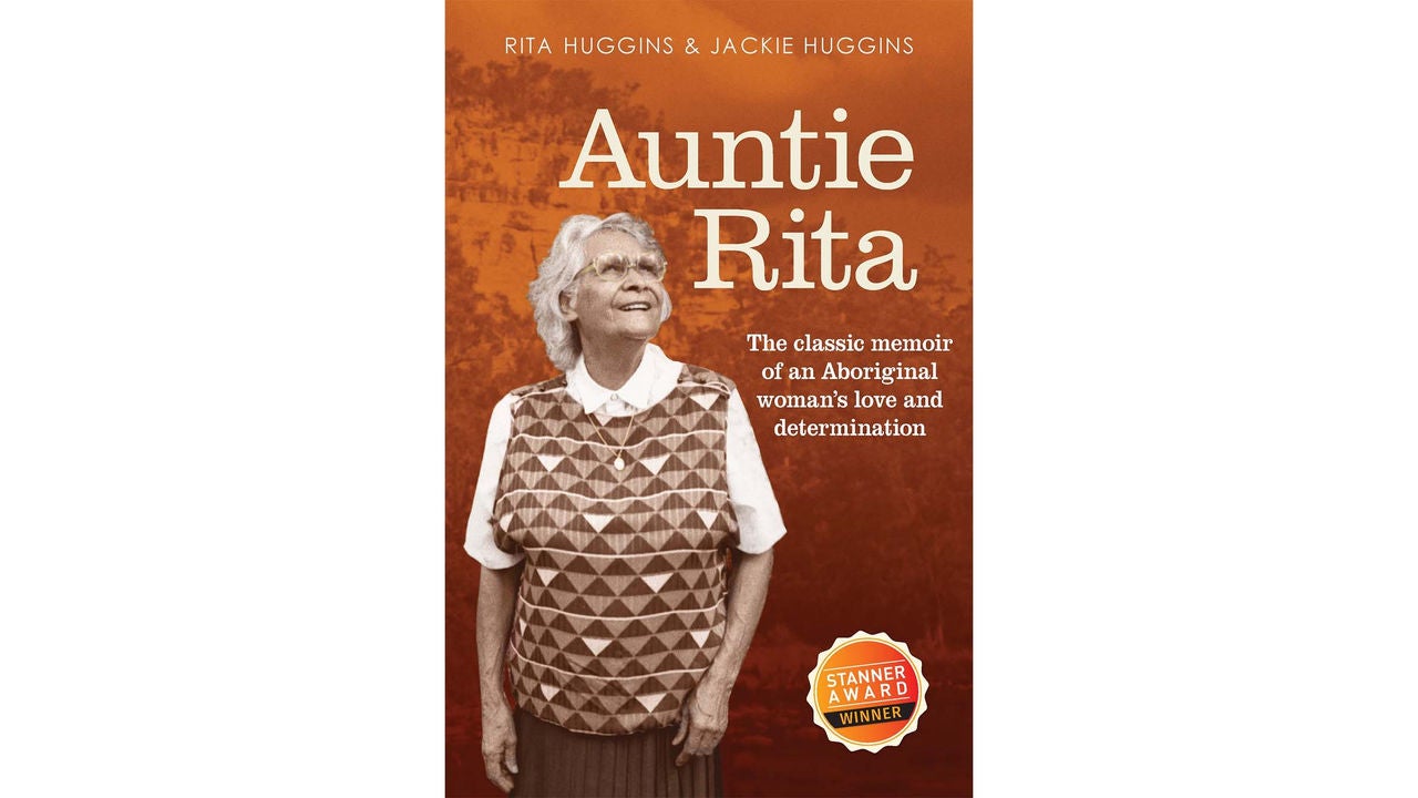 Book cover for 'Auntie Rita' by Rita Huggins and Jackie Huggins. The cover features a sepia-toned photograph of a woman in a patterned vest and skirt, standing against a warm brown background. Text highlights it as a classic memoir of an Aboriginal woman's love and determination. A visible 'STANNER AWARD WINNER' badge appears on the lower right.