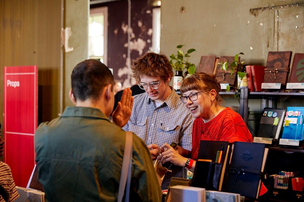 An image of stall holders at the Making Moves Market, smiling and talking to a customer.