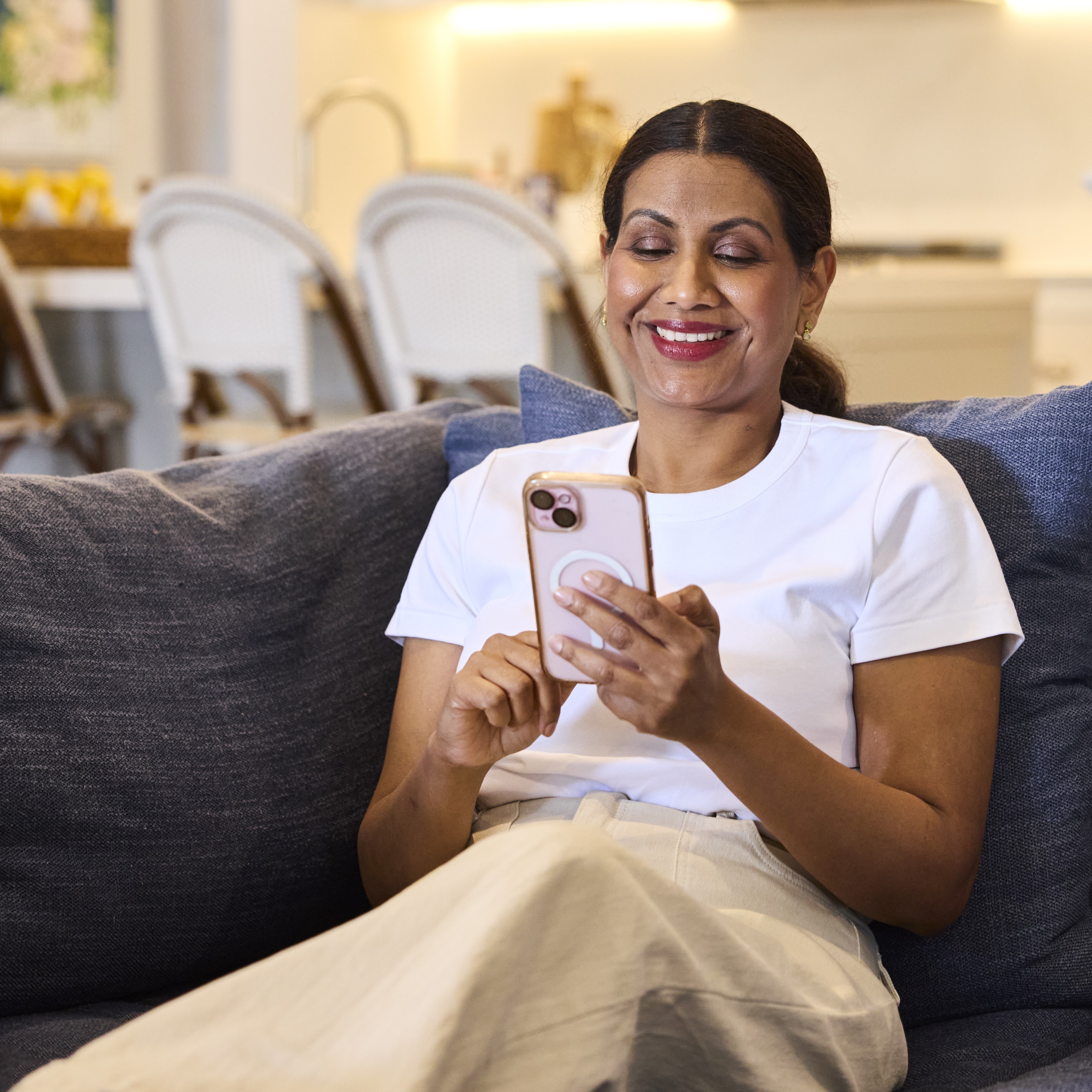 Person sitting on a couch in a living room, holding a smartphone.